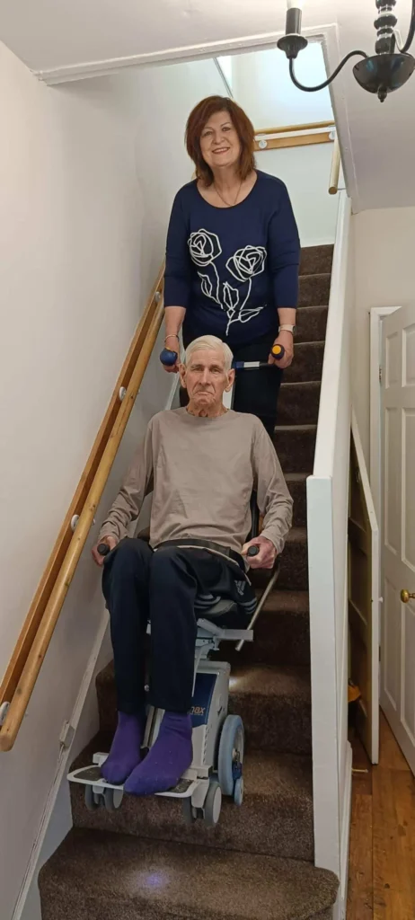 ageing man comes downstairs using a stairclimbing wheelchair