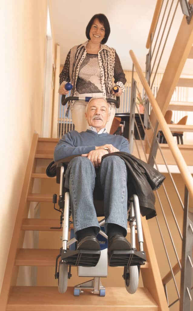 woman transfers elderly man upstairs with stair climbing wheelchair