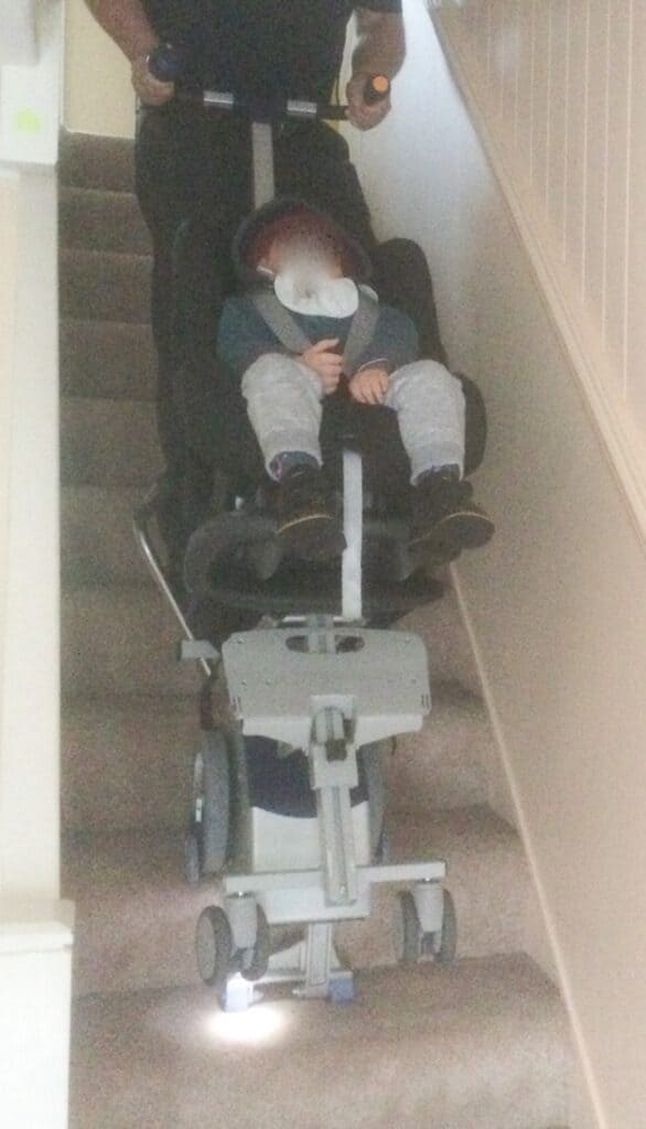 parent takes disabled child down stairs in stairclimber