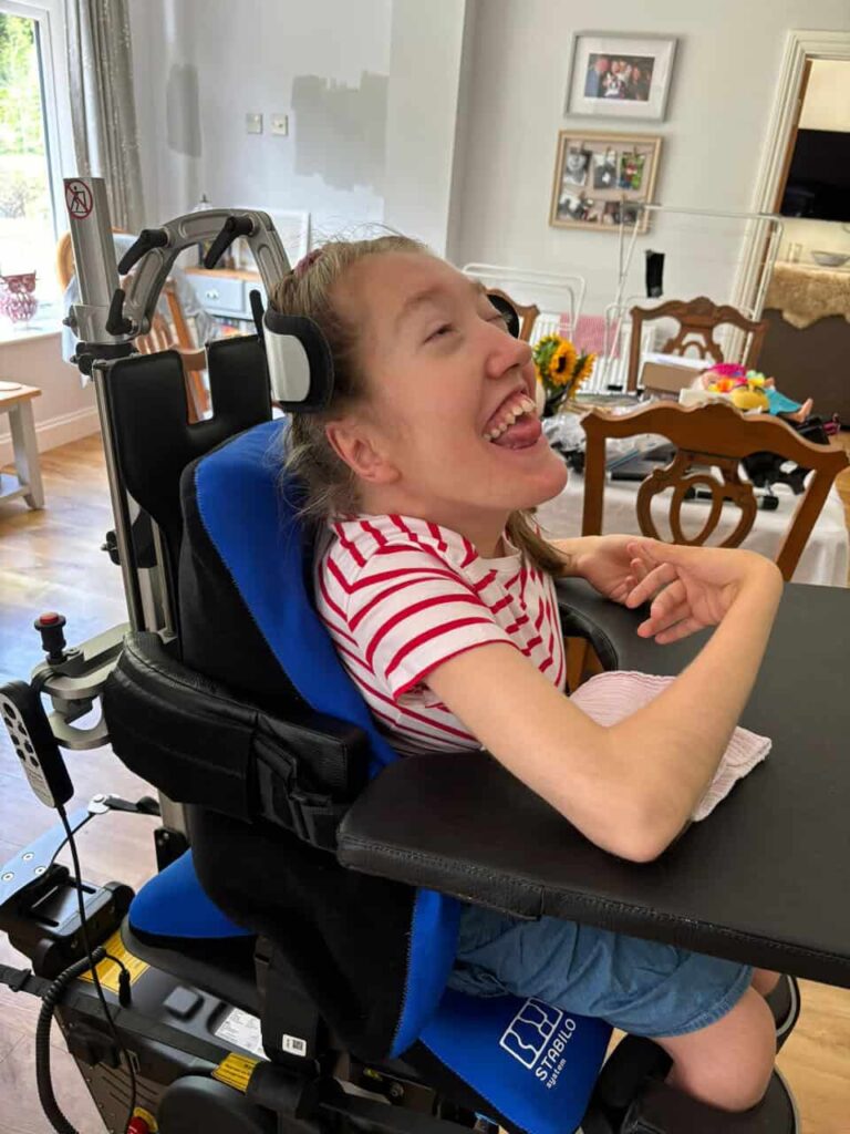 disabled girl laughs as she undergoes physical therapy using a walking aid