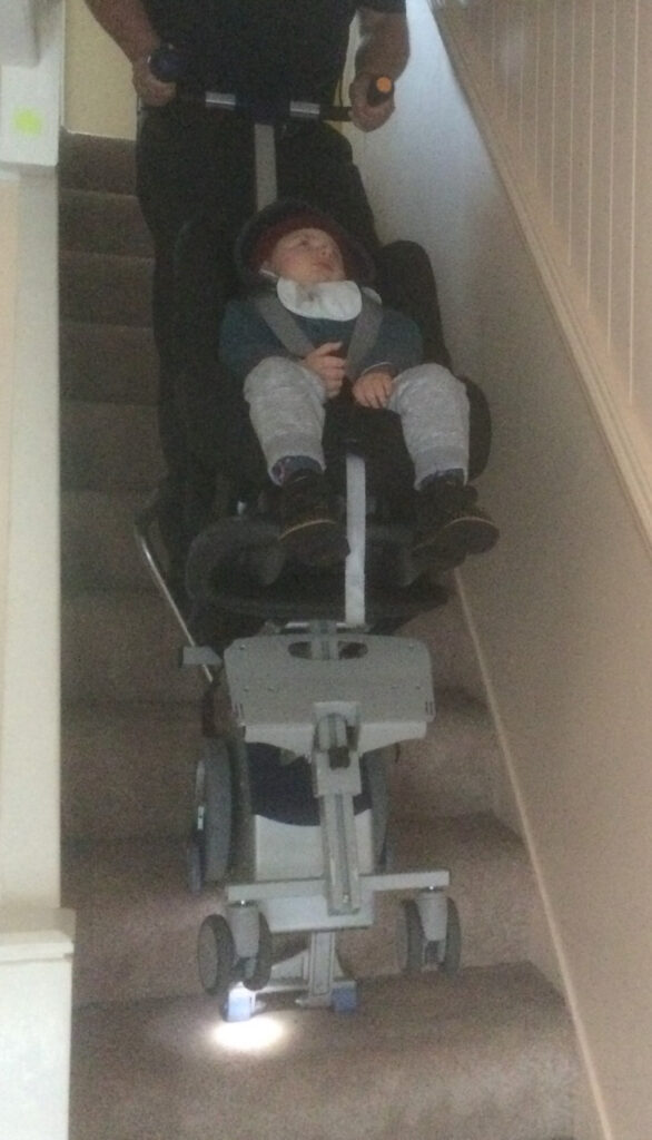 Young brain damaged boy comes downstairs on a stairclimber